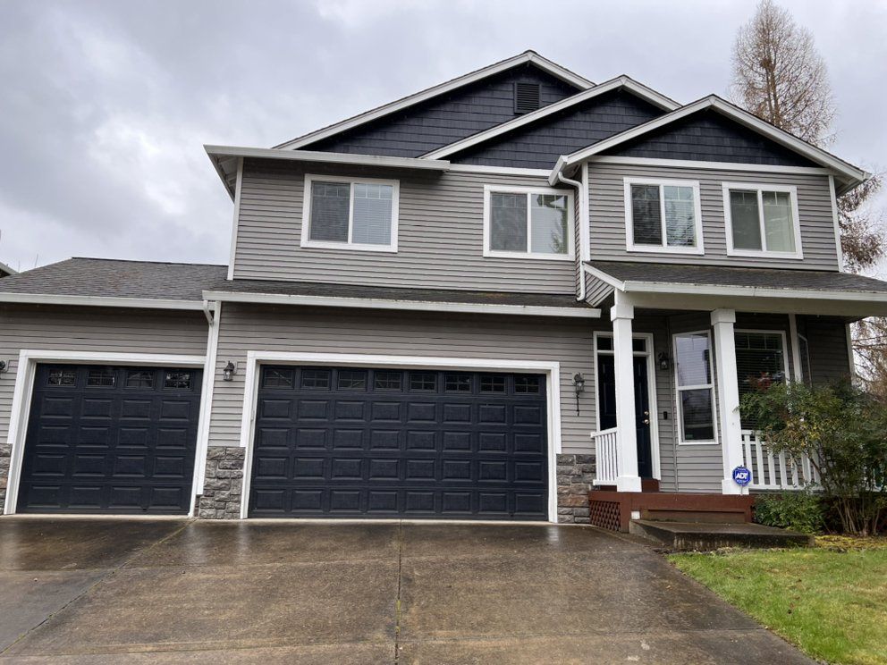 A large house with two garage doors and a driveway.