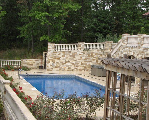 A large swimming pool with a stone wall surrounding it