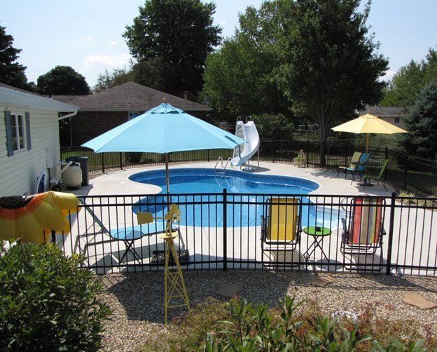 A fenced in backyard with a swimming pool and umbrellas