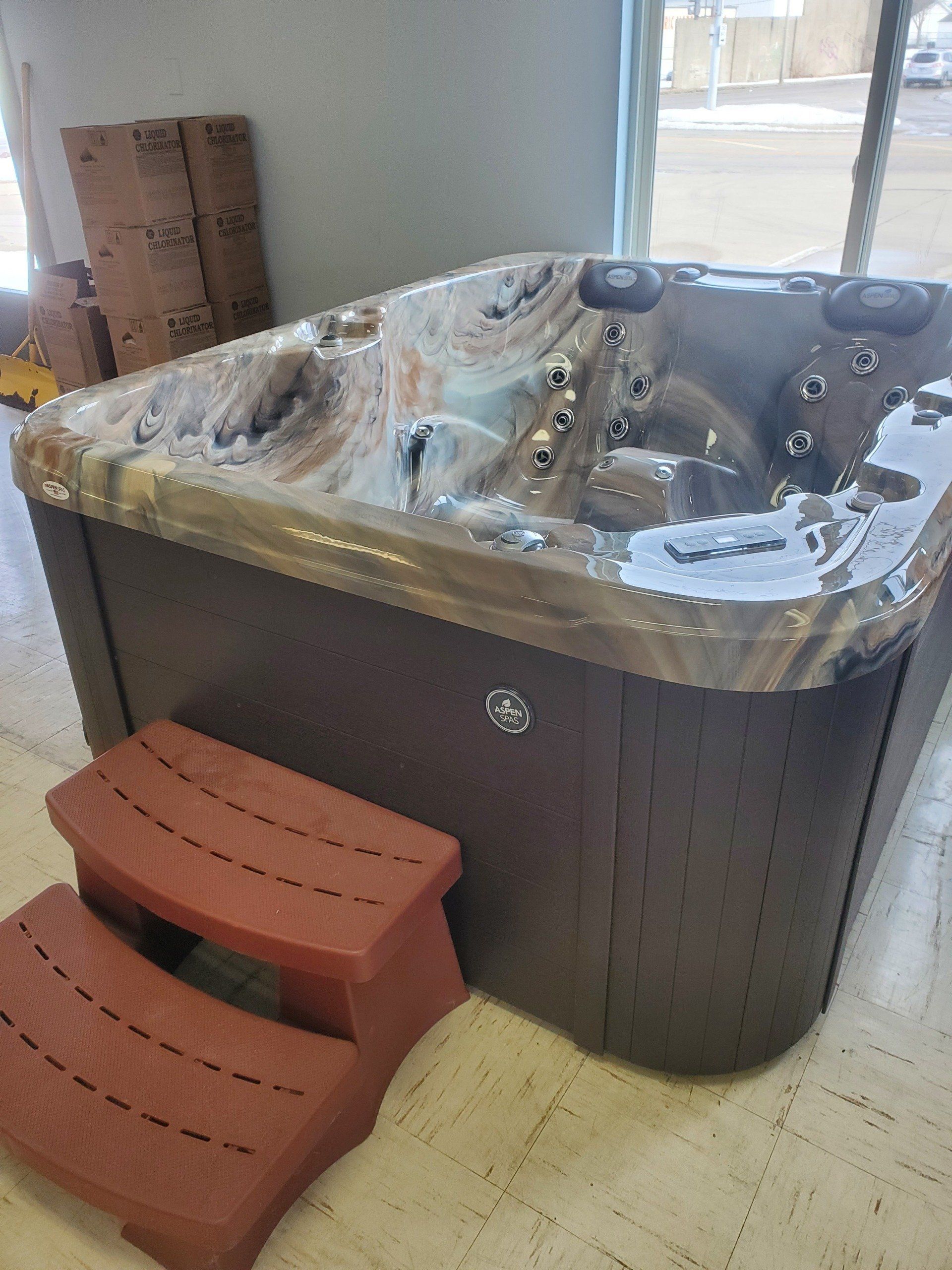 A hot tub is sitting on a tiled floor next to a red step stool.