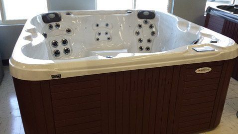 A white and brown hot tub is sitting on a tiled floor in a room.