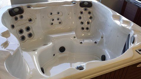 A white hot tub is sitting on top of a wooden table.
