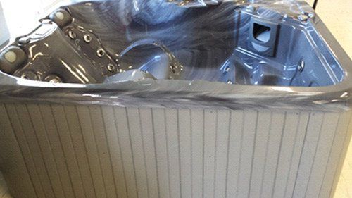 A black hot tub is sitting on a wooden floor.