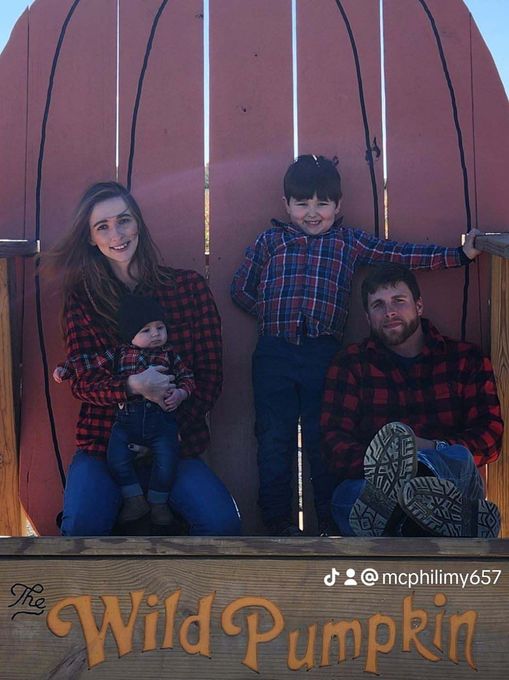 A family is posing for a picture in front of a large pumpkin.