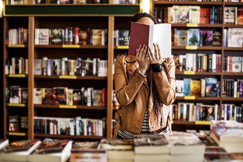 una ragazza in libreria che legge in piedi