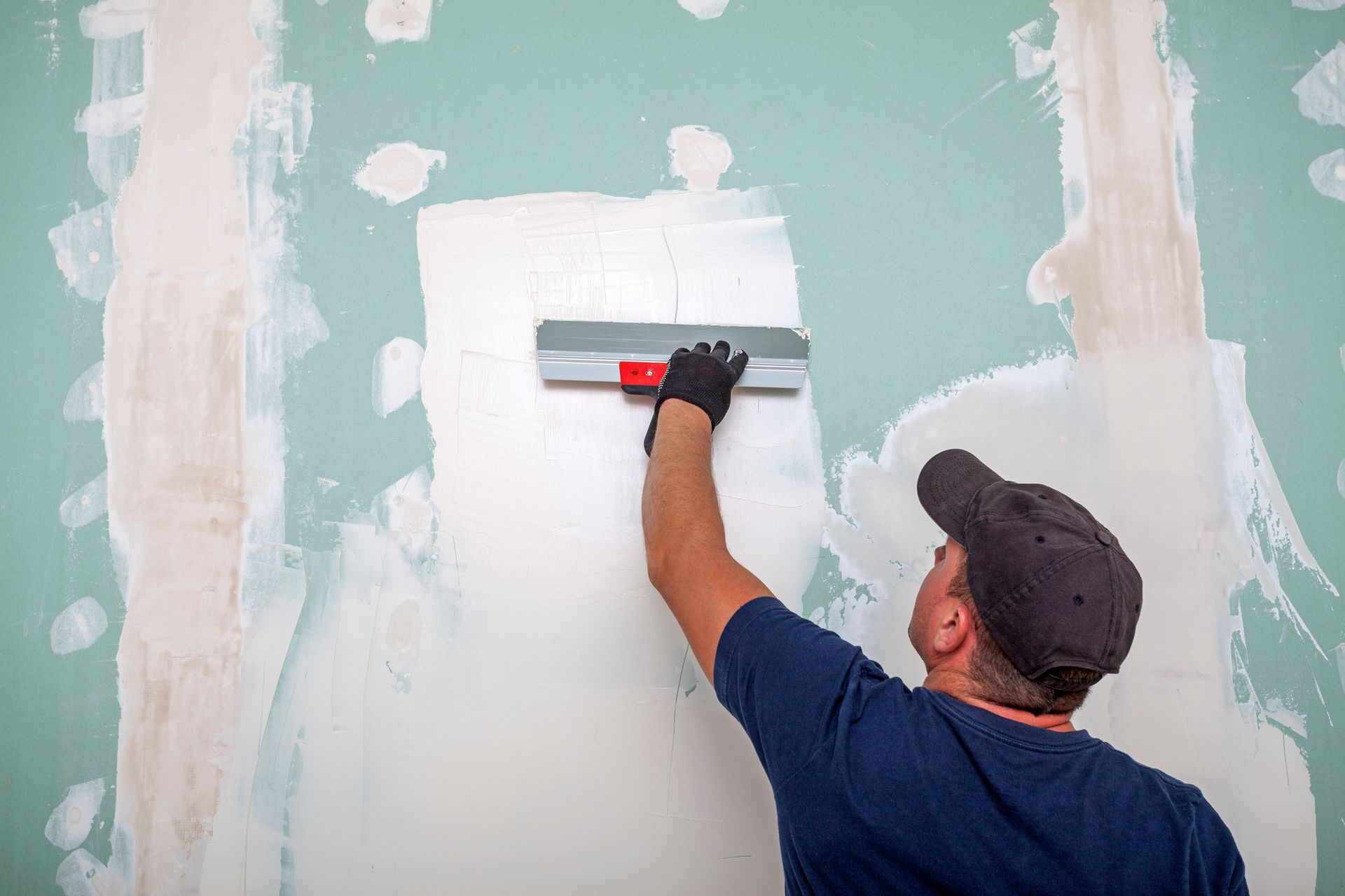 Person applying plaster to a wall with a trowel.