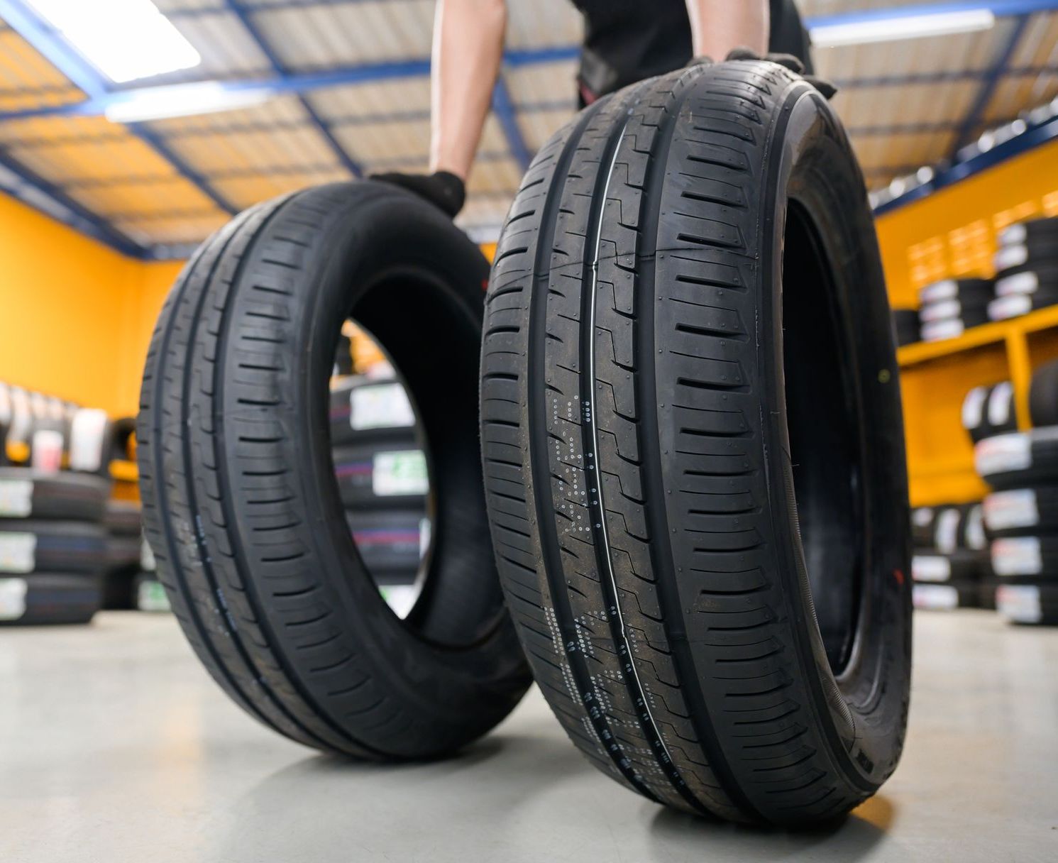 A Person is Holding Two Tyres in a Garage — Blackwall Tyre Service & Mechanical Repairs In Killcare, NSW