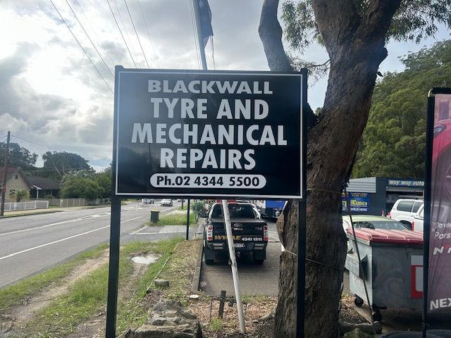 A Men in Front of a Sign That Says — Blackwall Tyre Service & Mechanical Repairs In Blackwall, NSW