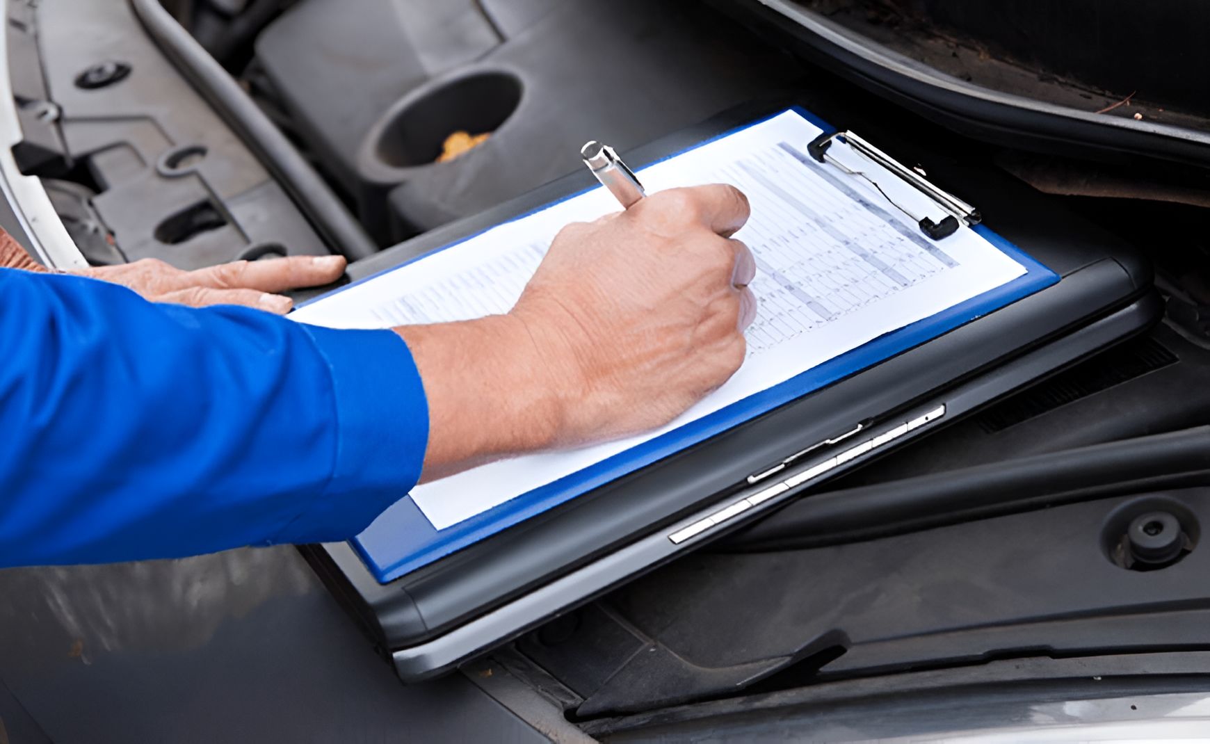 A Person is Writing on a Clipboard Under the Hood of a Car — Blackwall Tyre Service & Mechanical Repairs In Blackwall, NSW