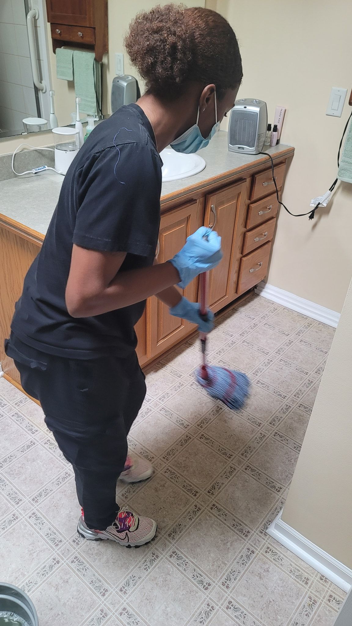 DAG personnel is cleaning the floor of a bathroom with a mop.