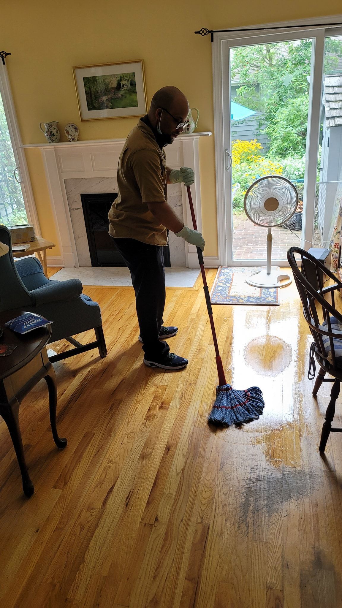 DAG owner David is cleaning a wooden floor with a mop in a living room.