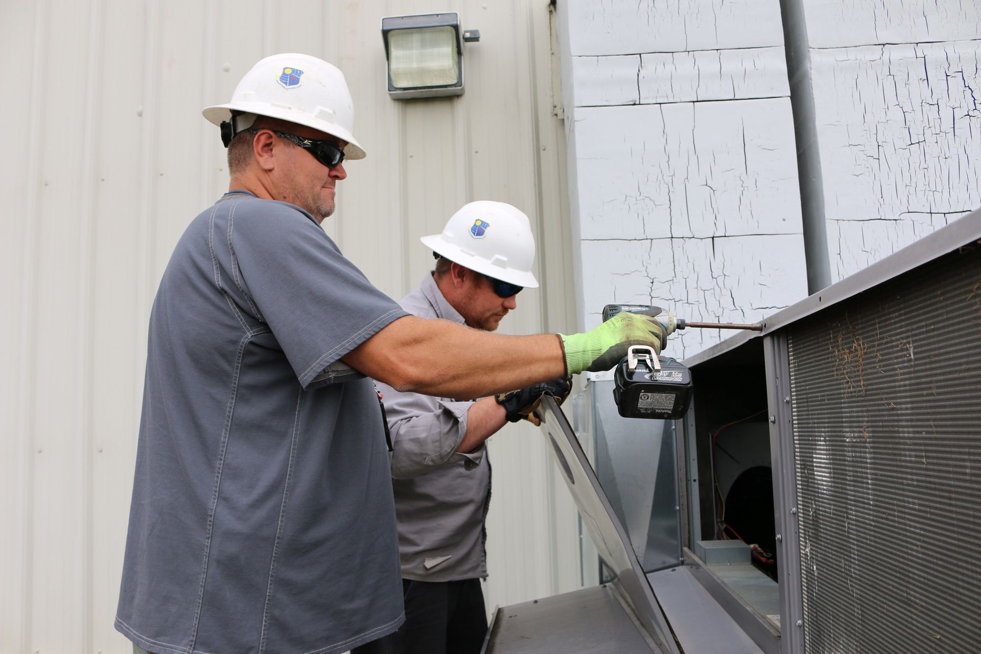 Two men wearing hard hats are working on a building.