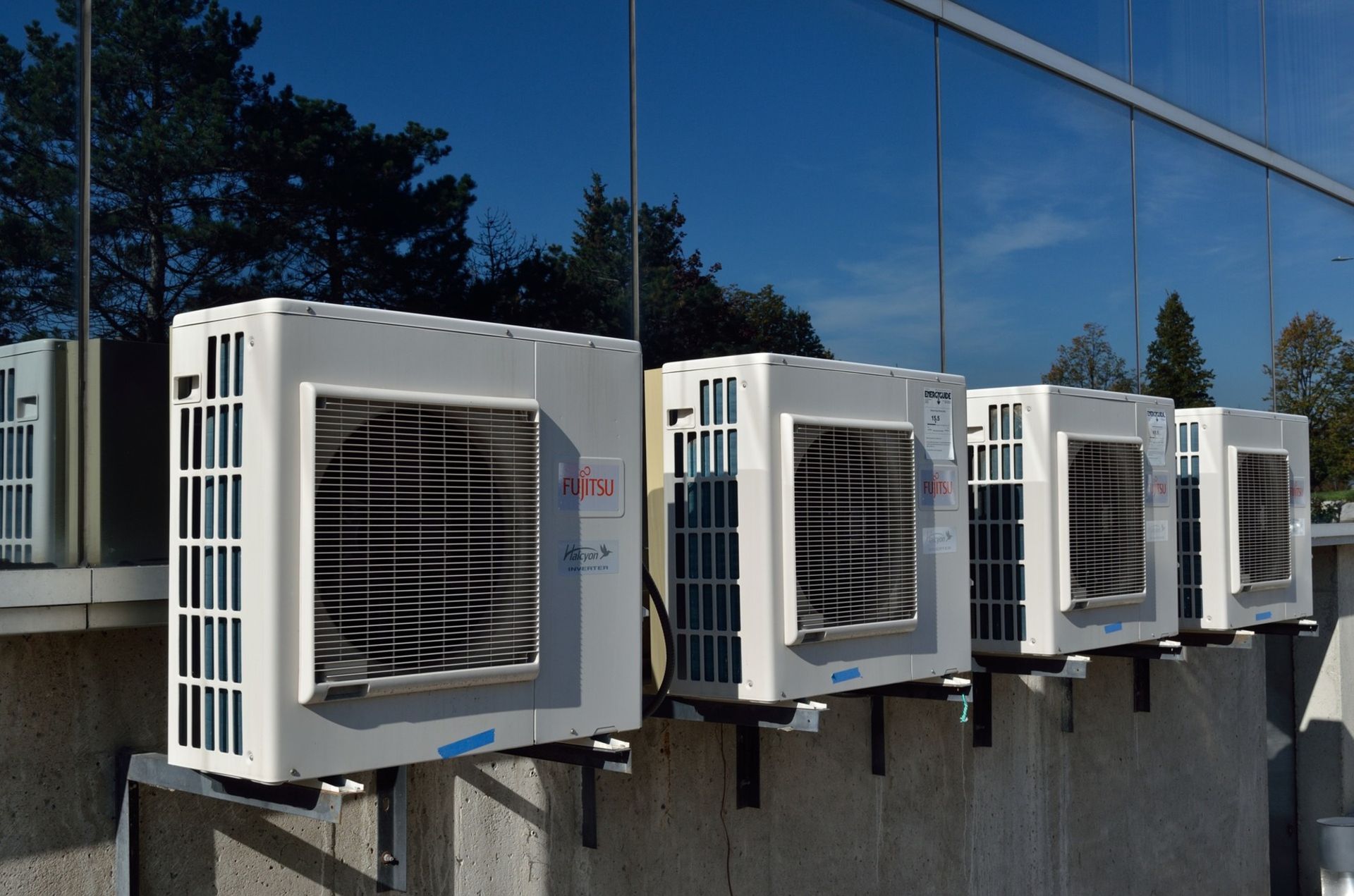A row of air conditioners are mounted to the side of a building