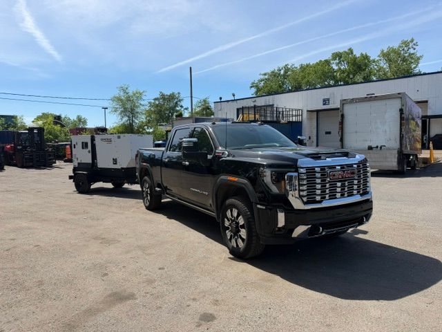Black pickup truck towing a white trailer in an industrial lot under a clear blue sky
