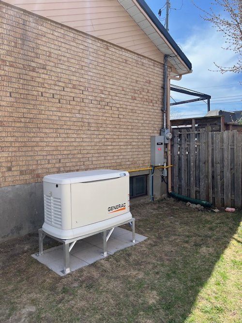Un générateur est installé dans l'arrière-cour d'une maison en briques.