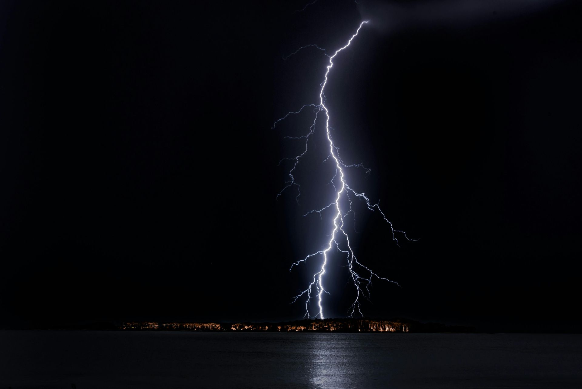 Lightning strikes over a body of water at night