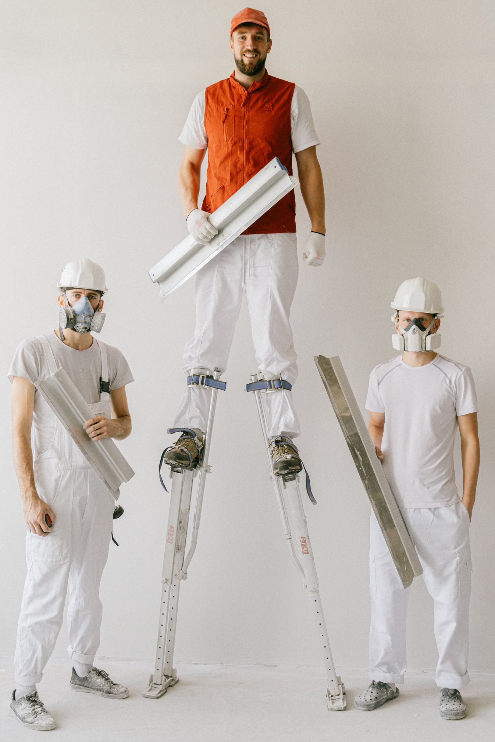 3 men fixing drywall with one man on stilts