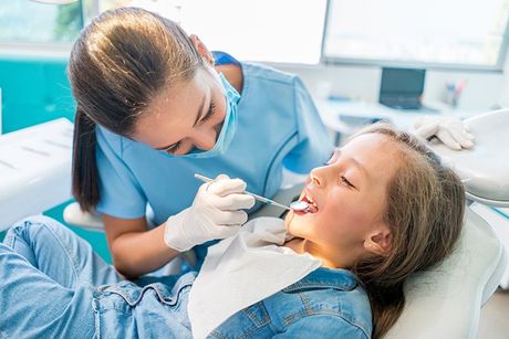nurse in blue examining patients teeth