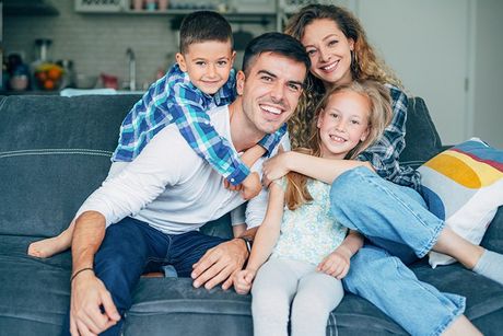 Family of 4 smiling on couch