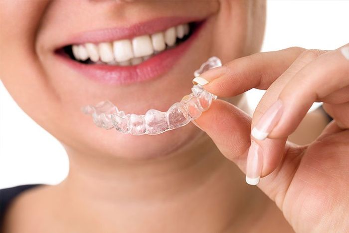 woman smiling with invisalign in  hand