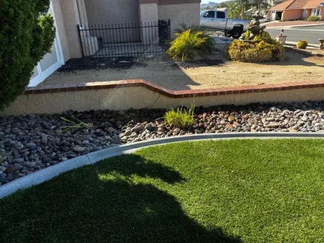 Landscaped yard with lawn, rock beds, brick retaining wall, and house in the background.