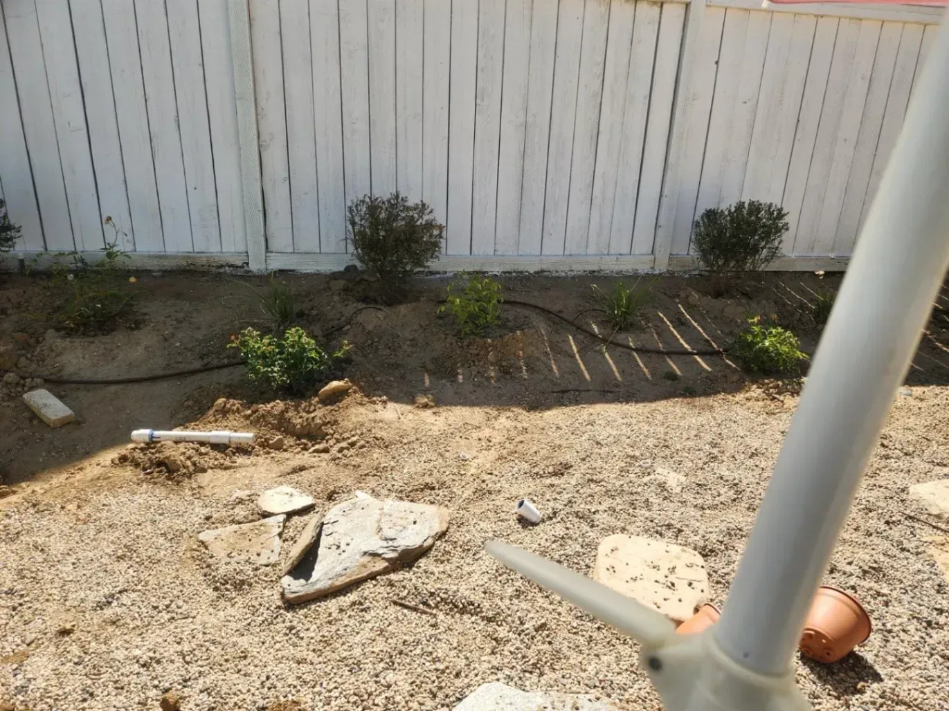 Garden bed with shrubs and a white fence.