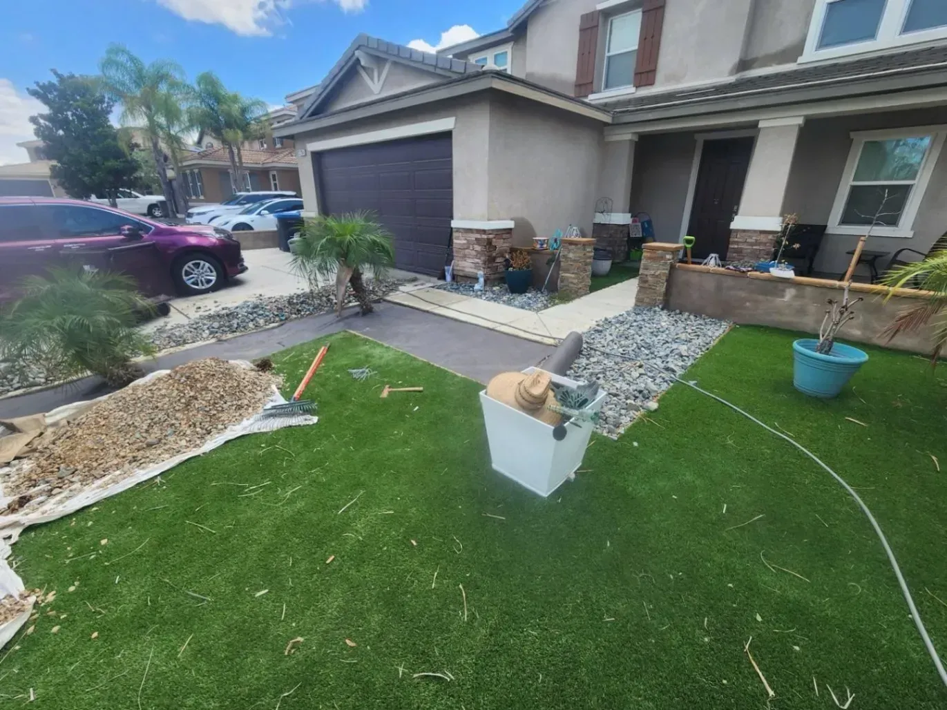 Front yard with artificial turf and a house with a brown garage door and landscaping.
