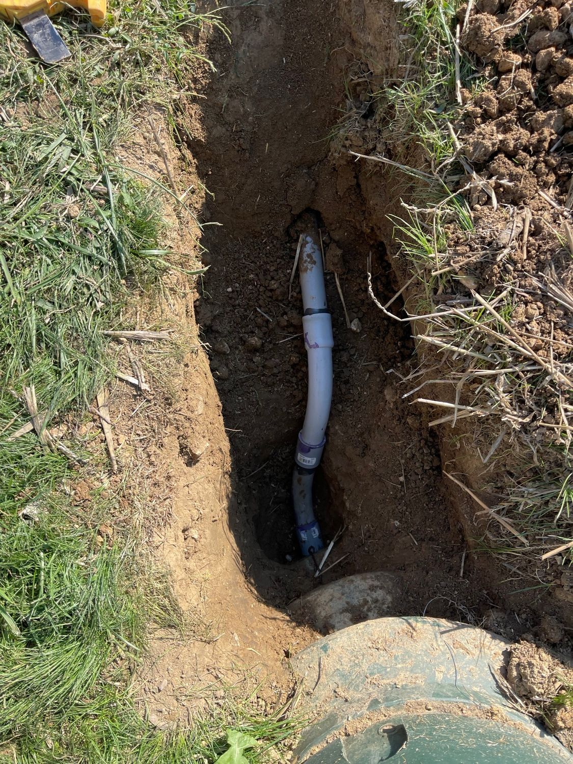 A pipe is laying in the dirt in a hole.