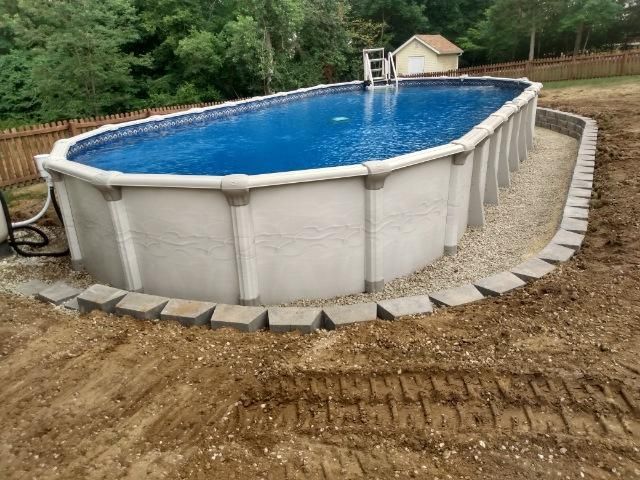A large swimming pool is sitting in the middle of a dirt field.