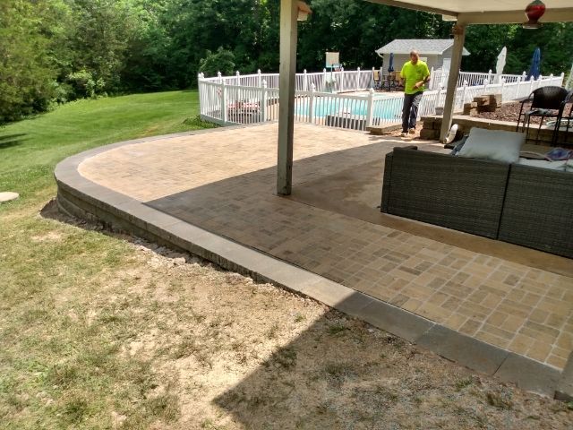 A man is standing on a patio next to a pool.