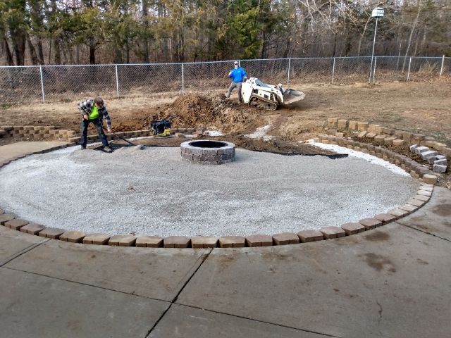 A fire pit is being built in the middle of a concrete patio.