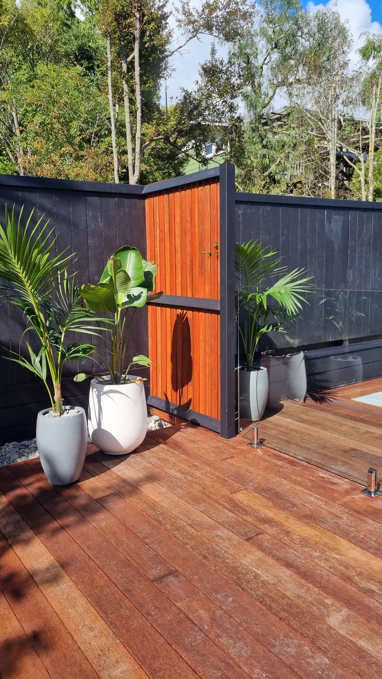 A fence with a wooden gate and potted plants in front of it.