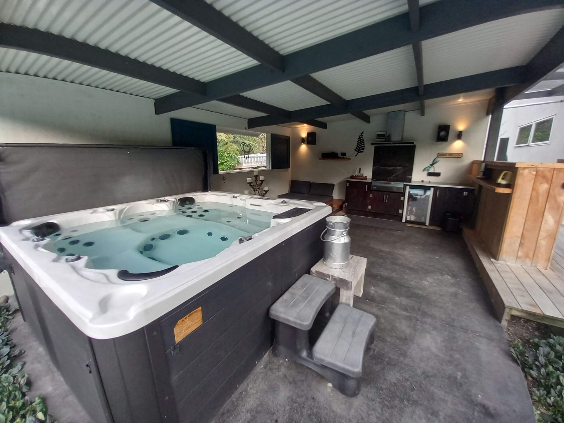 A large hot tub is sitting under a roof in a room.
