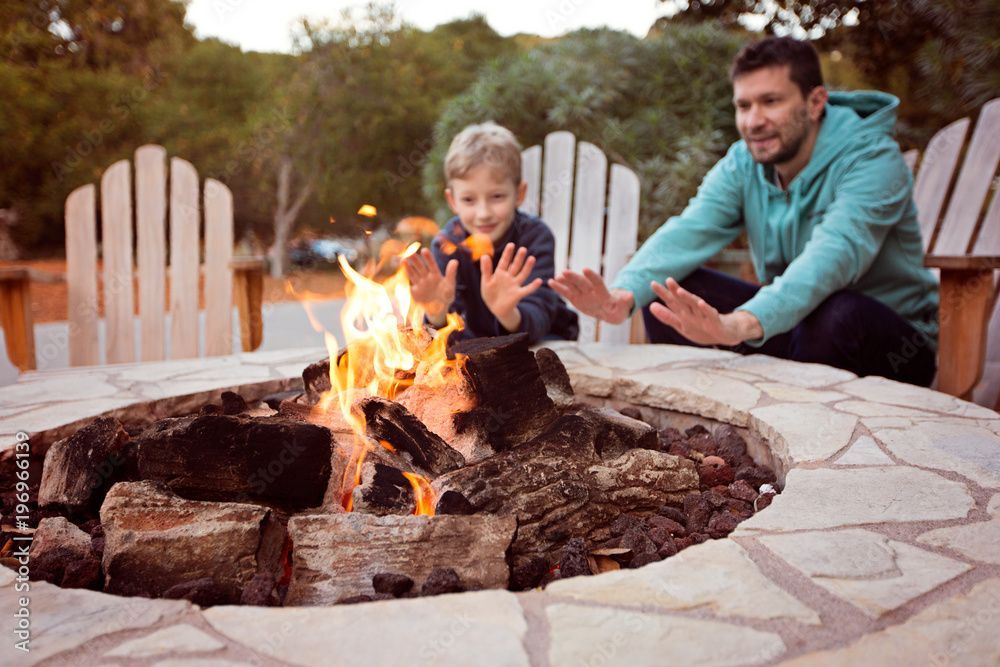 A man and a boy are sitting around a fire pit.