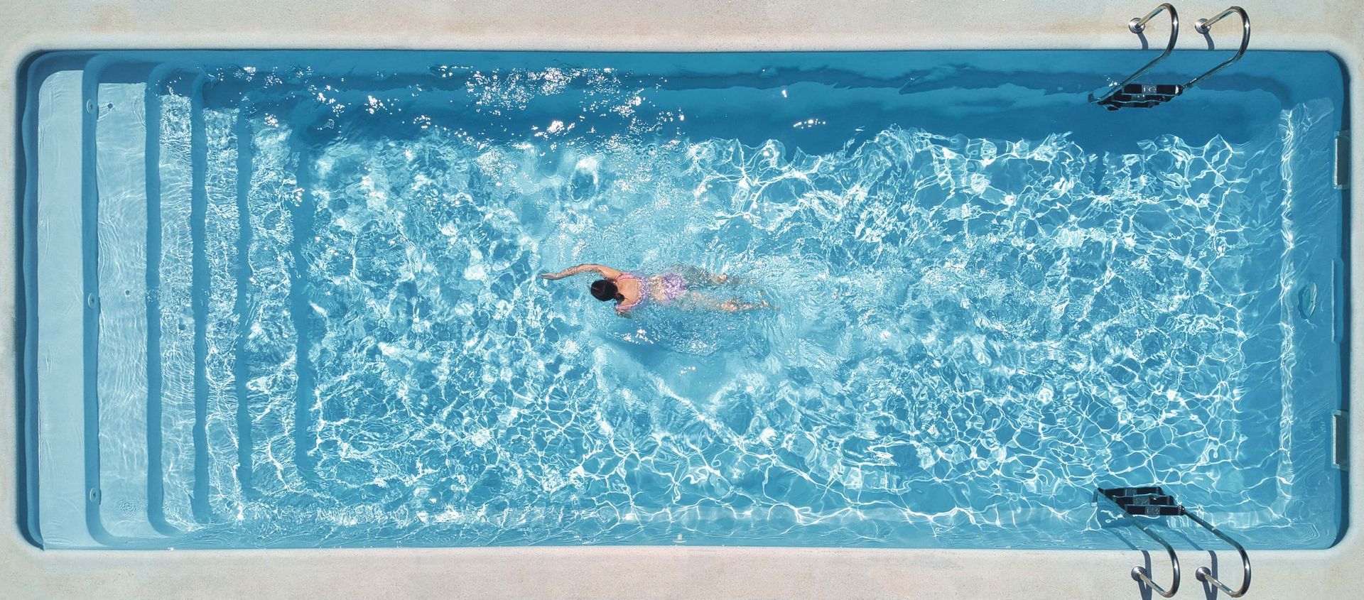 A person is swimming in a large swimming pool.