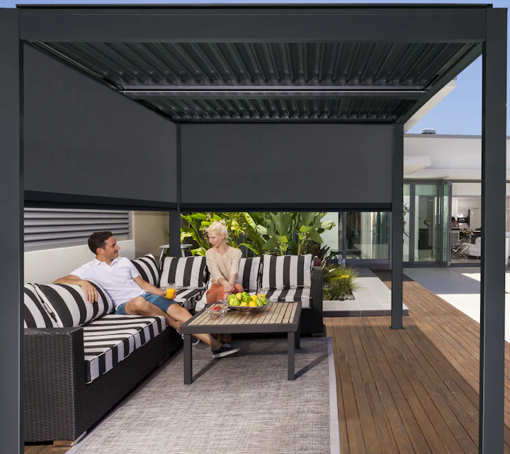 A man and woman are sitting on a couch under a pergola