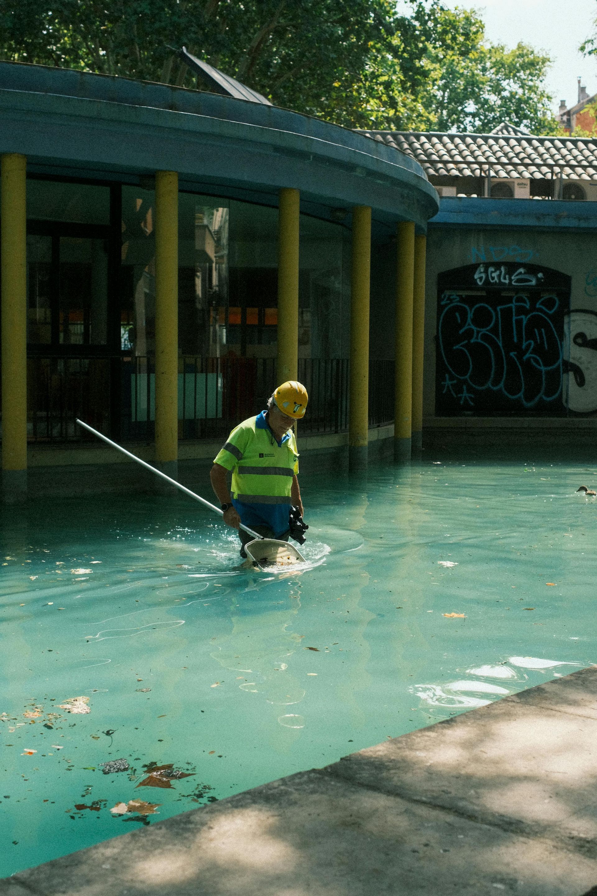 A man in a yellow hard hat is standing in a pool of water.