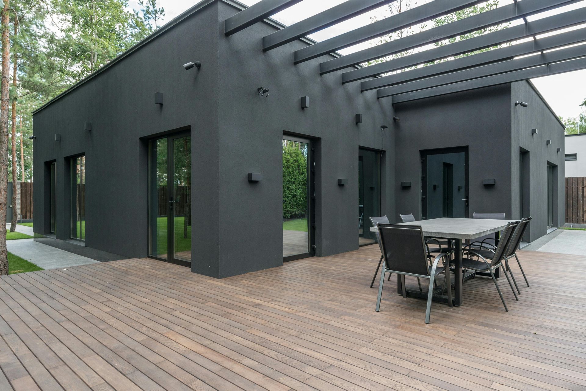 A black house with a wooden deck and a table and chairs on it.