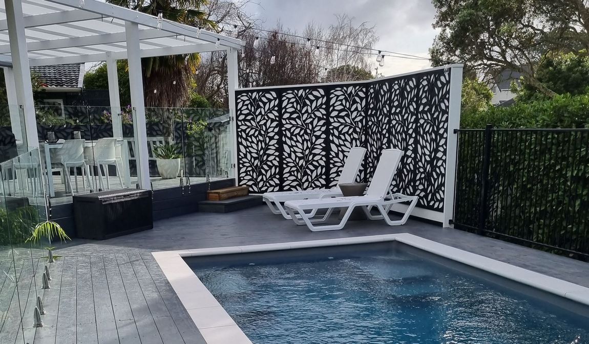A large swimming pool surrounded by chairs and a pergola.