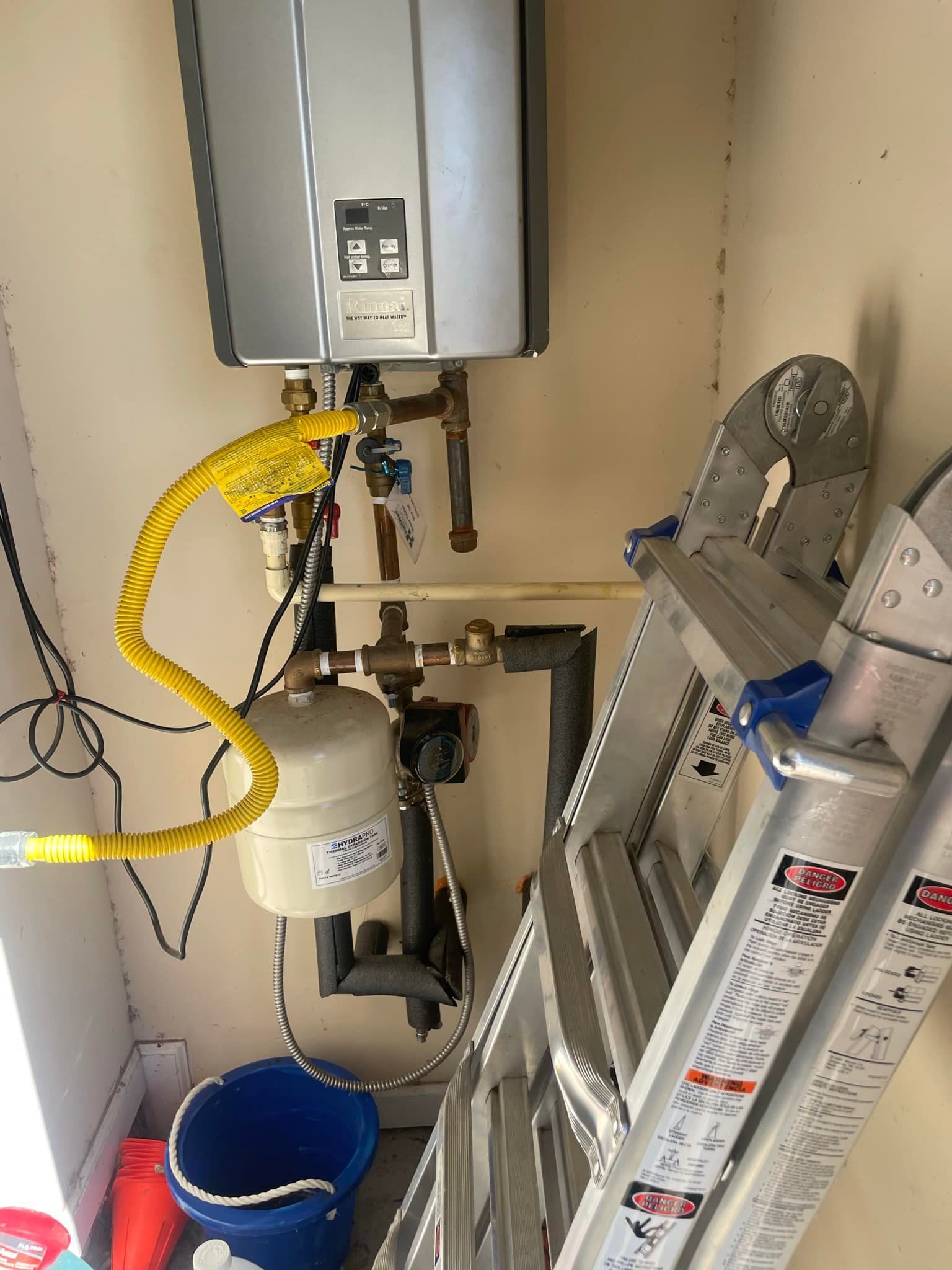 A ladder is sitting next to a water heater in a room.