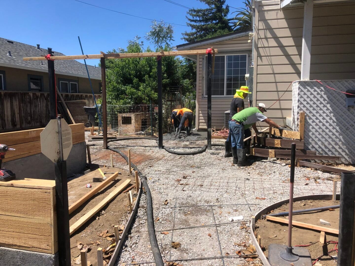 A group of men are working on a concrete walkway in front of a house.