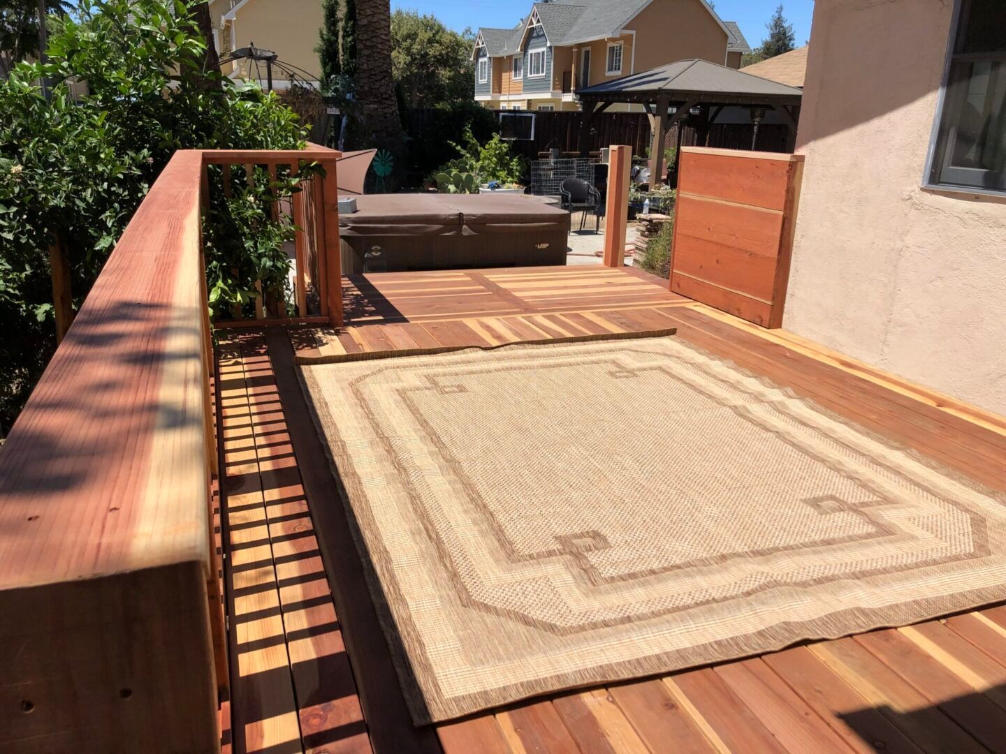 A wooden deck with a rug on it and a hot tub in the background