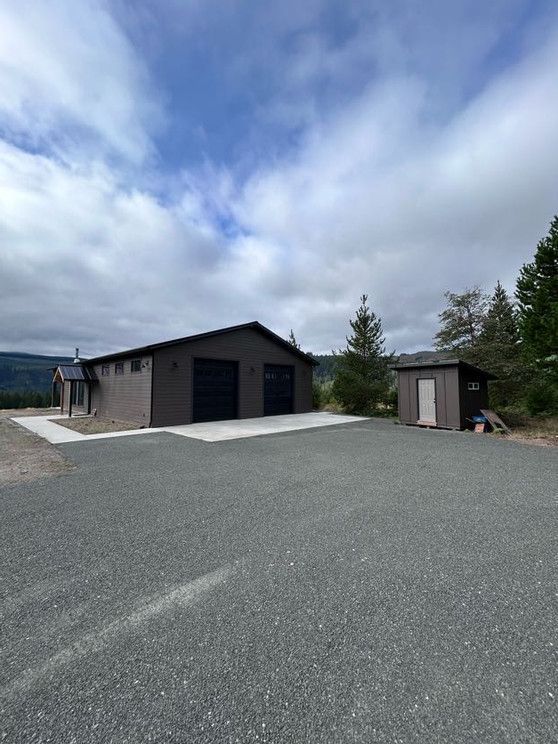 A garage and a shed are sitting next to each other on a gravel road.