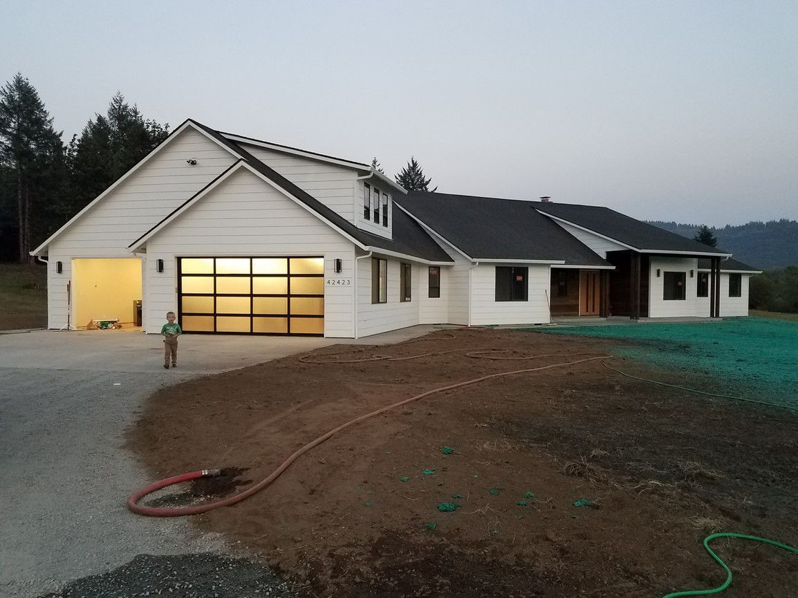 A white house with a black roof and a glass garage door