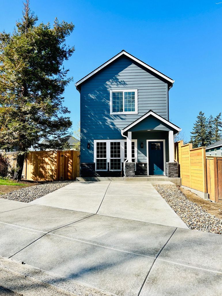 A blue house with a concrete driveway in front of it