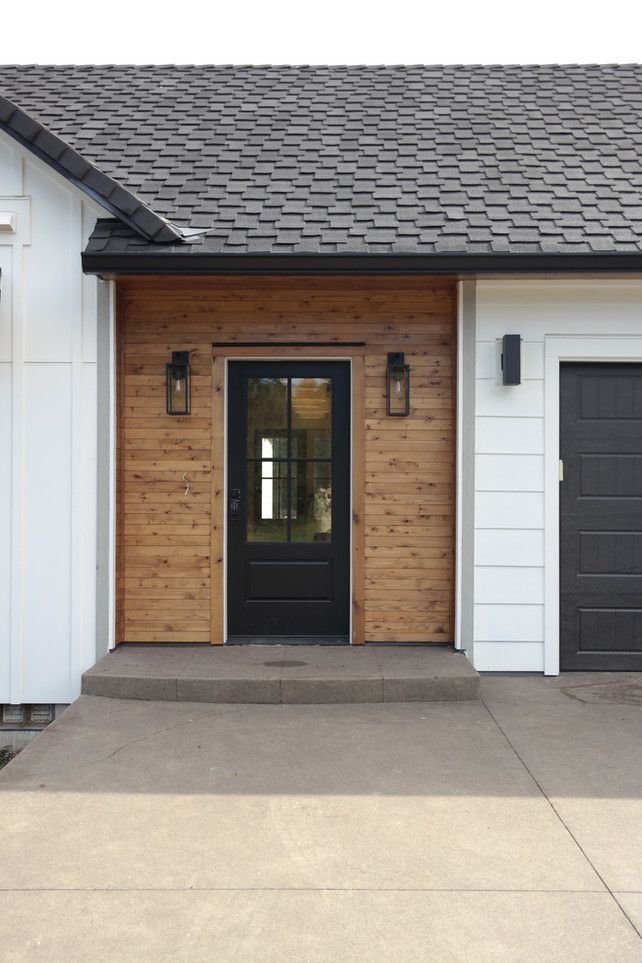 A white house with a black door and a black garage door.