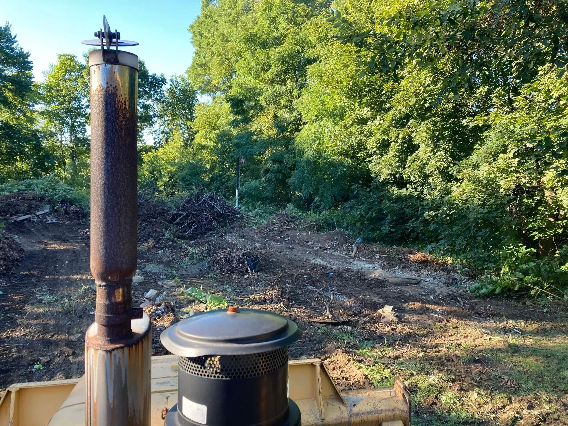 Rusty outdoor pump beside a metal tank in a wooded clearing