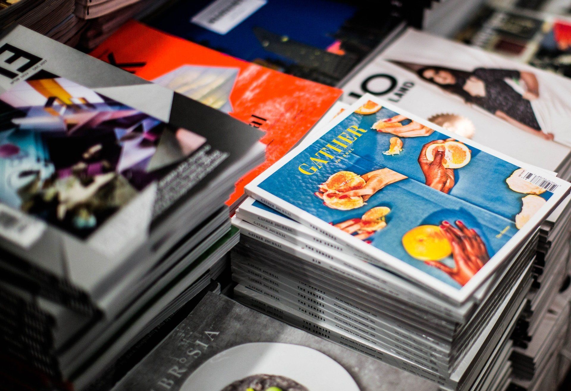 A bunch of magazines are stacked on top of each other on a table.