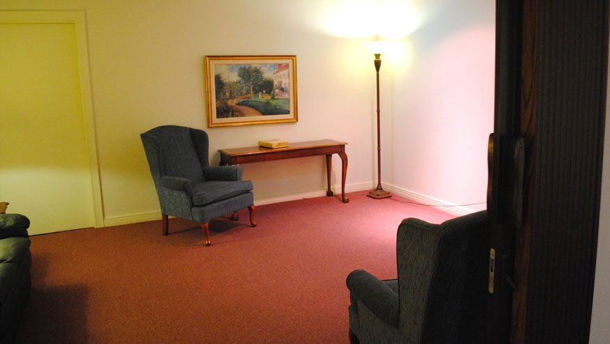 a living room with two chairs a table and a lamp