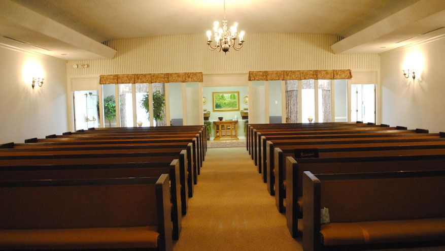 a church with rows of benches and a chandelier hanging from the ceiling .